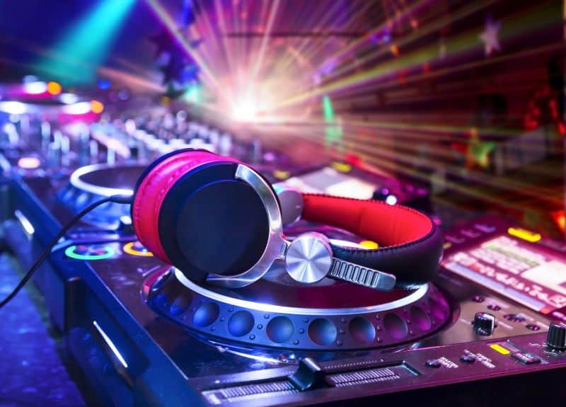 Dj mixer with headphones at nightclub.  In the background laser light show